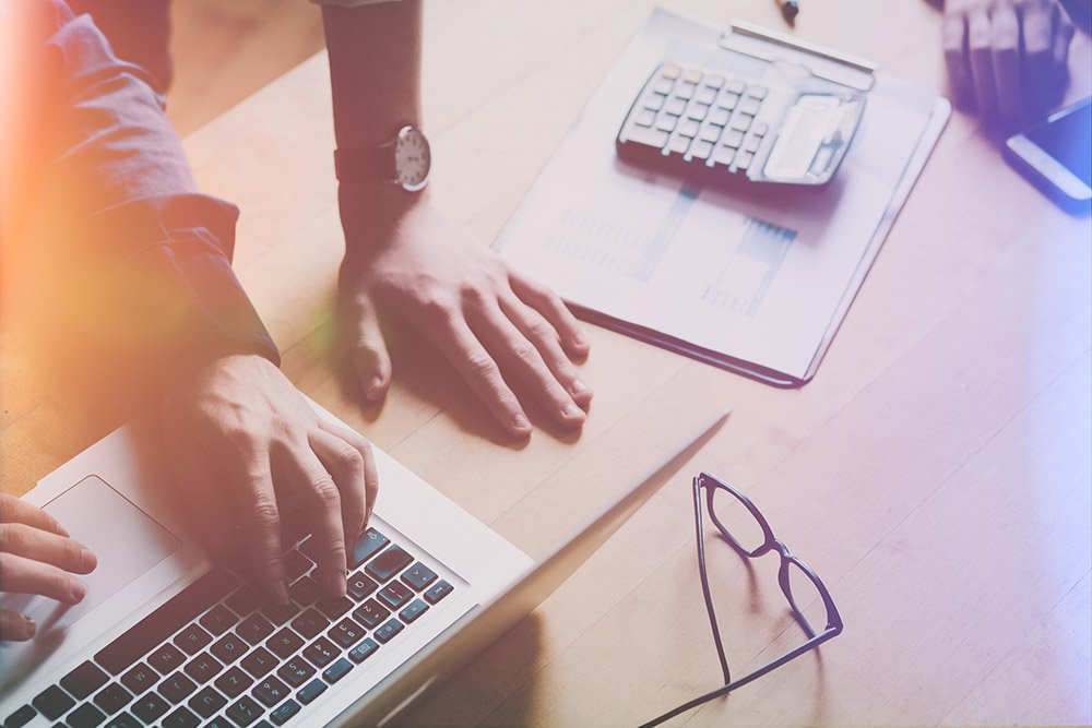 Business team analyzing report on laptop computer at office desk in joined effort coworking